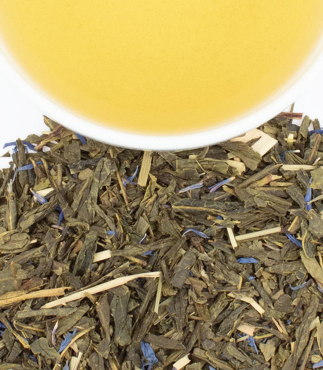 Loose leaf blueberry green tea blend with a cup of brewed yellow-green tea