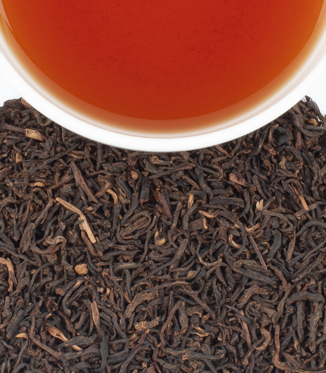 Close-up of chai tea leaves with a cup of tea in the background