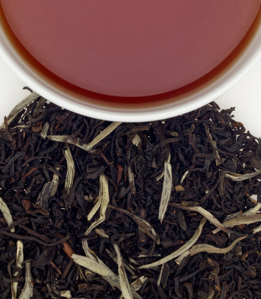 Black tea leaves with a cup of tea in the background - blinks emporium