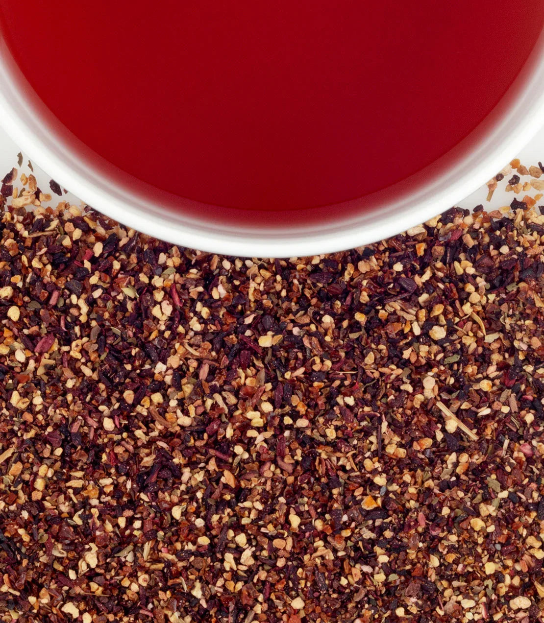Raspberry herbal tea in white cup with loose leaf blend on white background