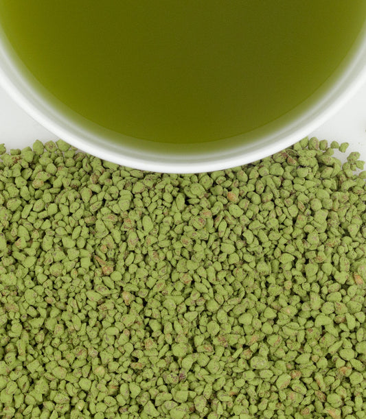 Green tea powder with a cup of green tea in the background
