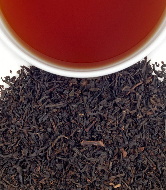 Titanic Blend loose leaf black tea beside a cup of brewed tea on white background