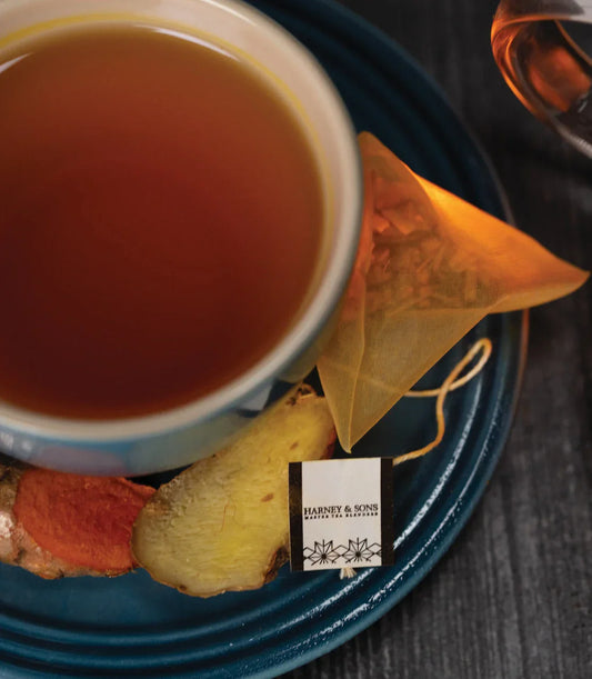 Cup of herbal tea with Harney & Sons organic ginger turmeric tea sachet on blue plate