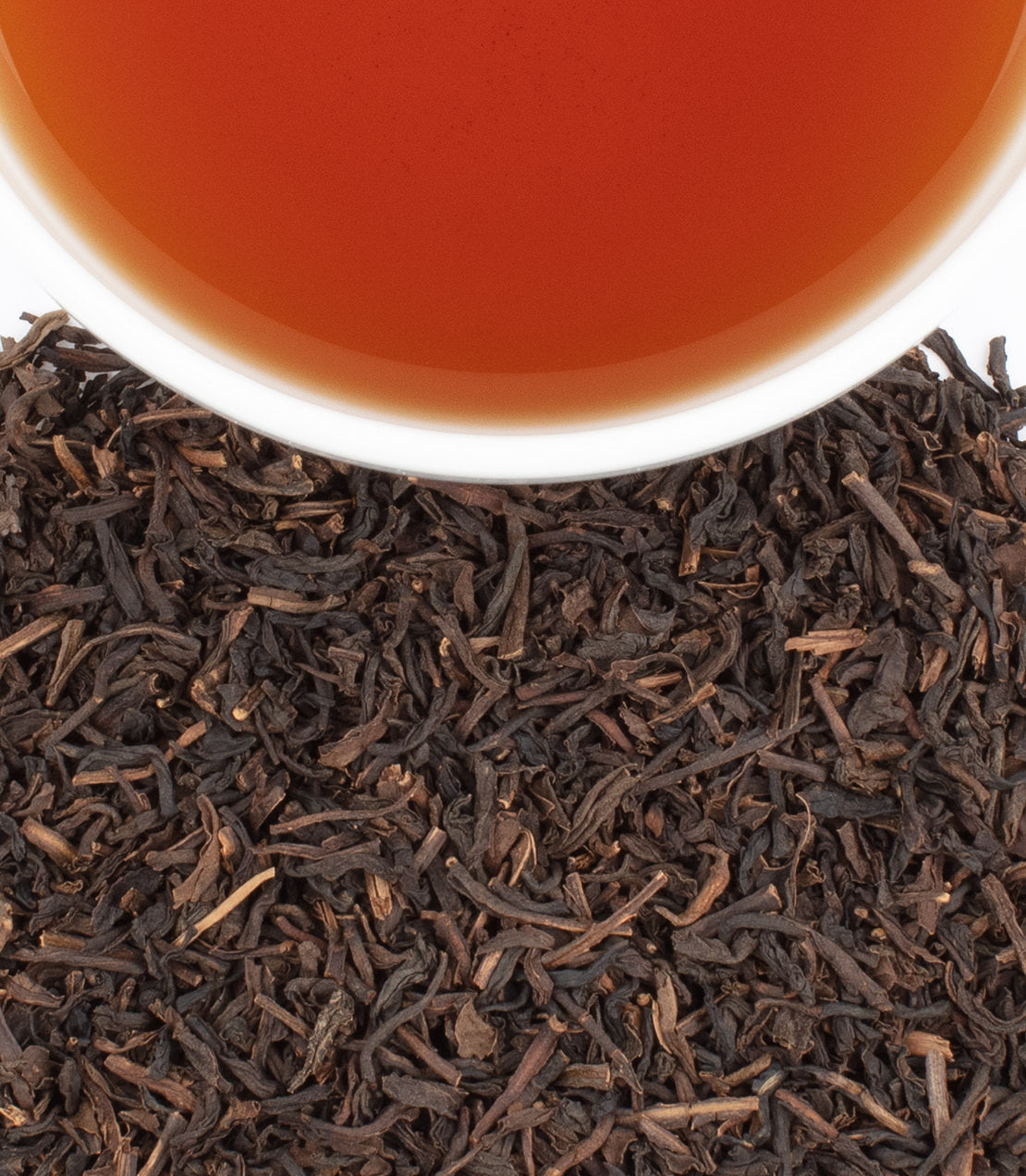 Cup of brewed decaf tea with loose leaf black tea on white background