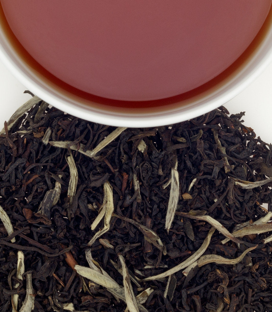 Black tea leaves with a cup of tea in the background - blinks emporium