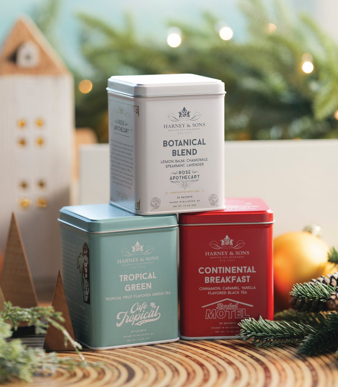 Three tea tins stacked on a wooden surface with a festive background